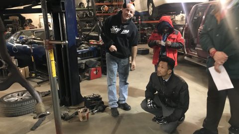 Kevin looking at underside of car Discovery with Olney Students
