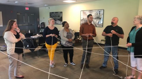 Photo of a people in a training room engaged in a group activity with string