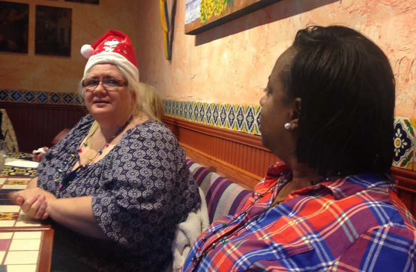 Diane and Shauna seated at a Networks’ holiday party. Diane is donning a Santa hat.
