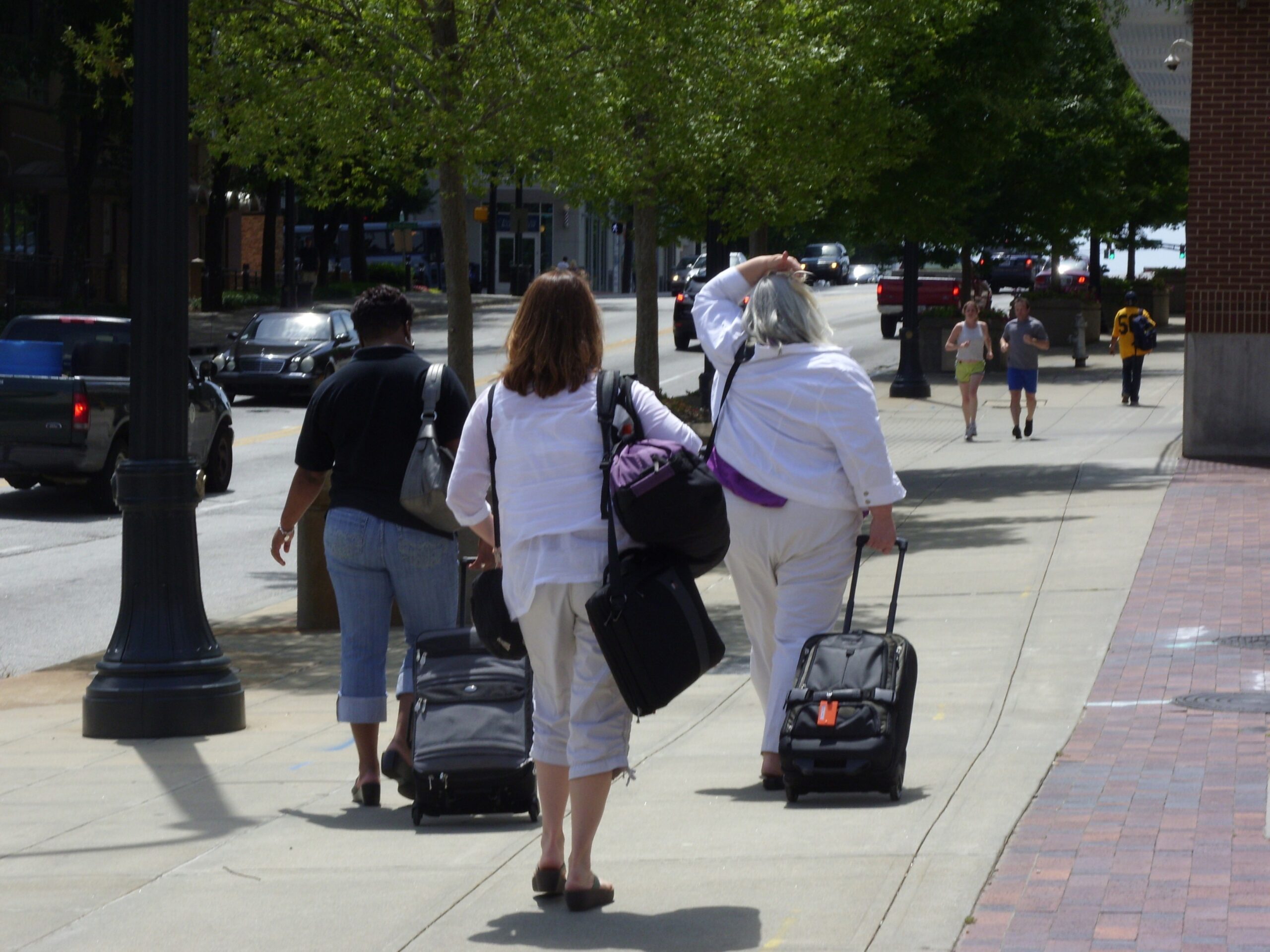 Diane Shauna, and Jill are lugging their baggage down the sidewalk.