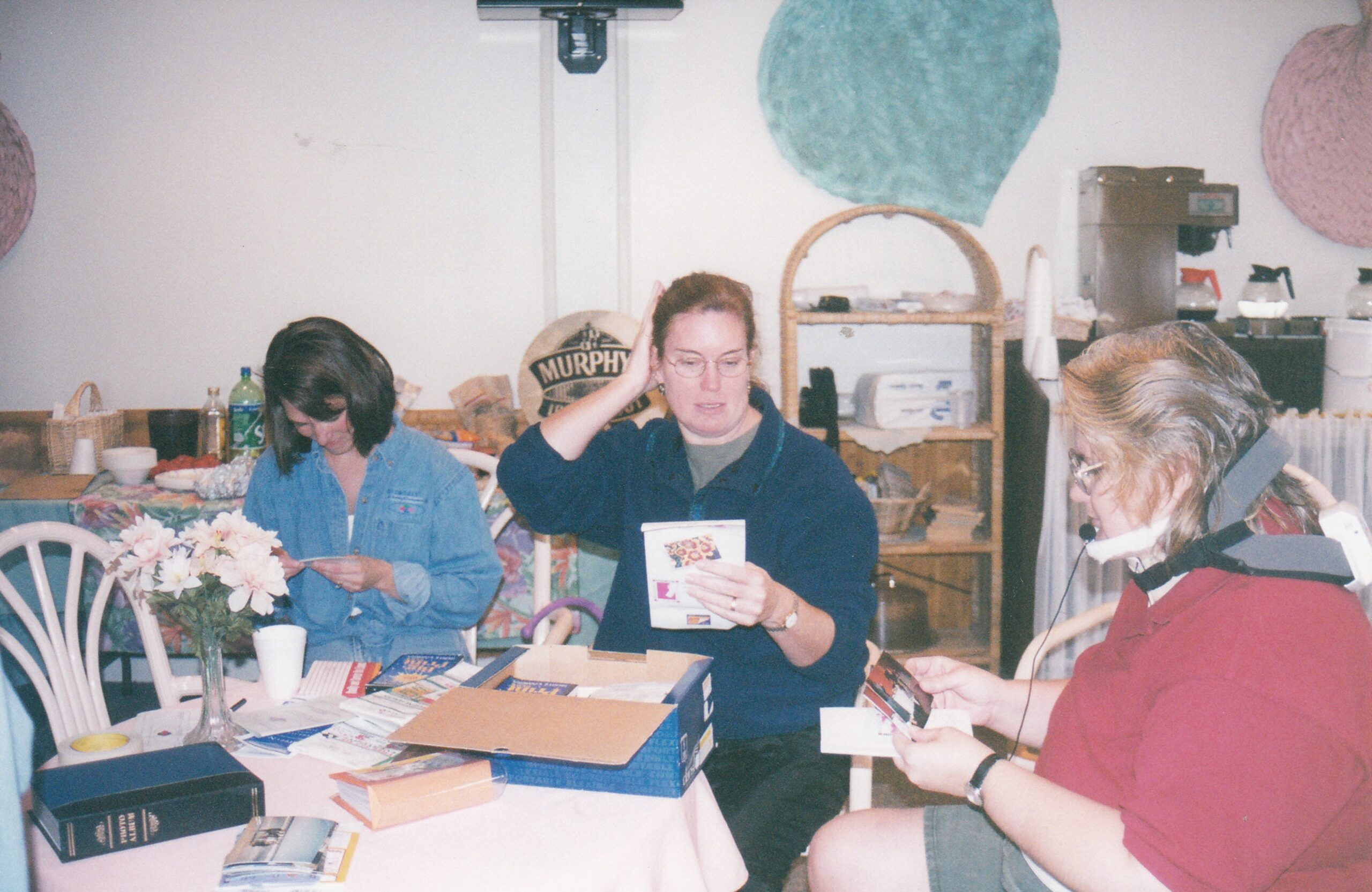 Diane and two others seated at a table going through photo albums.