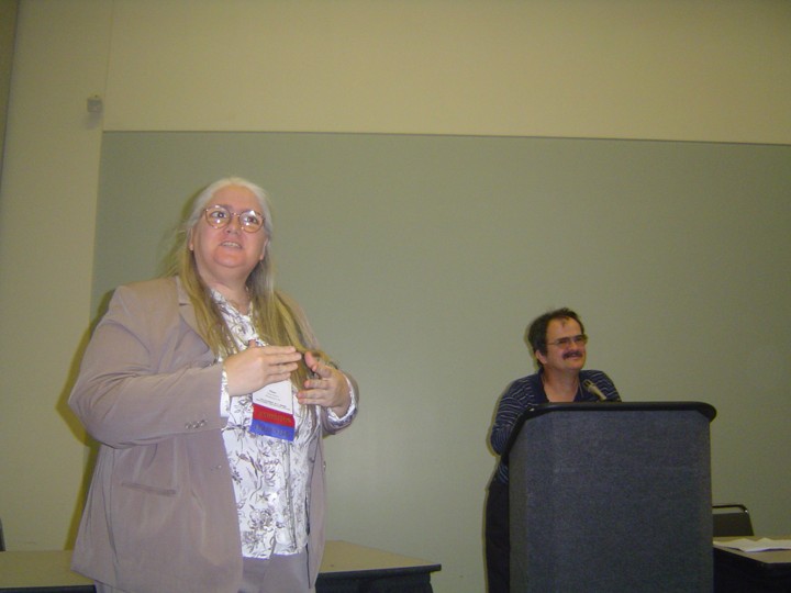 Diane and George at a conference presentation. George is standing at the podium.
