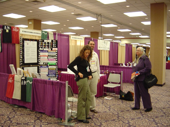 Michael and Megan Landes and Diane standing near Networks exhibit booth at a conference.