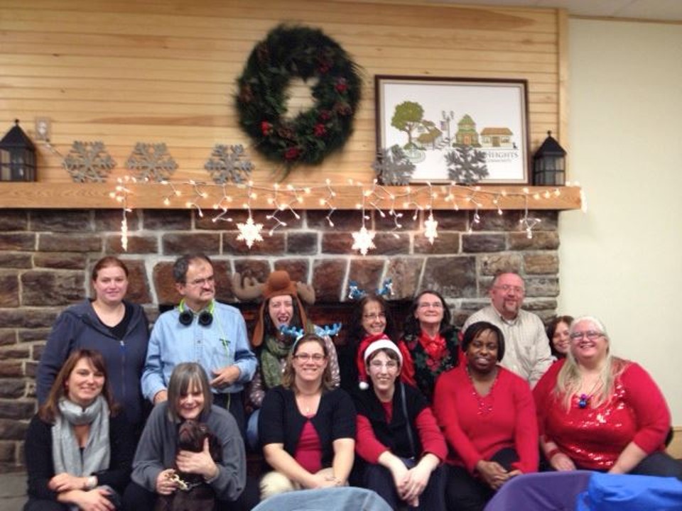Stacey, Jill, Suzanne (and guide dog), George, Julia, Jess, Tracy, Nancy, Shauna, Joe, Doris, and Diane posing at a holiday party.