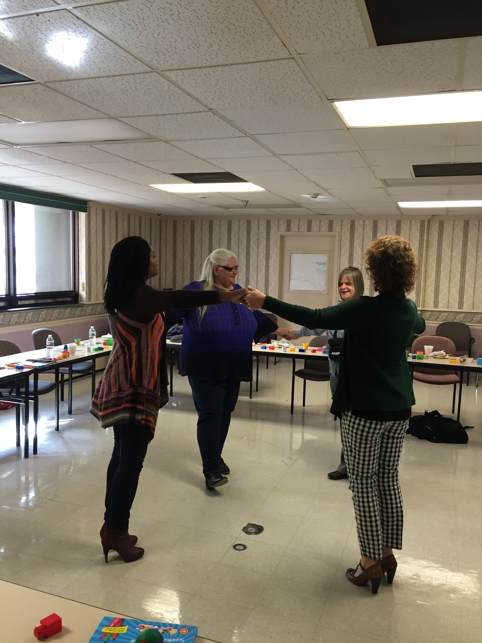 Diane, Suzanne and others forming a circle using their arms extended towards each other.